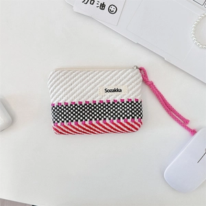 Close-up of a striped cotton makeup pouch with a pink zipper pull on a desk