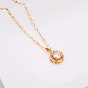 Close-up of golden round pendant necklace with zircon crystals on a white plate