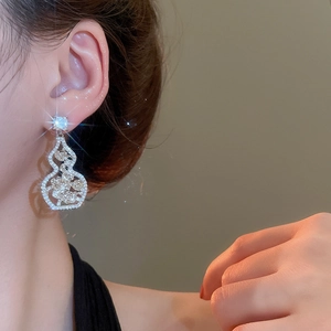 Macro detail of silver needle flower gourd earrings inlaid with sparkling white zircons