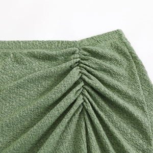 Close-up of sage green ruched bikini fabric with 3D seersucker texture and elastic details