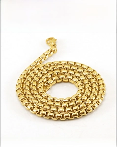 Gros plan d'un collier chaîne box en acier inoxydable plaqué or 18K avec fermoir mousqueton