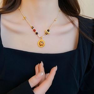 Detail of gold woven necklace with colorful beads and hollow round pendant on neck