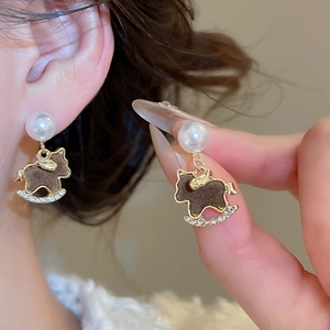 Detail of gold rocking horse earring with pearls and zircon micro-inlay on ear