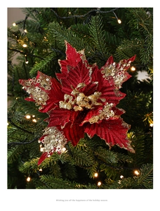 Close-up of red flocked Christmas flower with gold sequins on festive tree branches