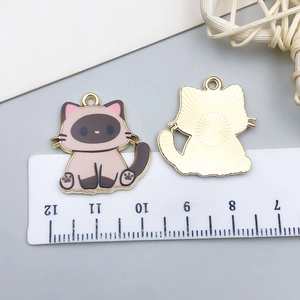 Detailed size measurement of a Siamese cat enamel pendant next to a metric ruler