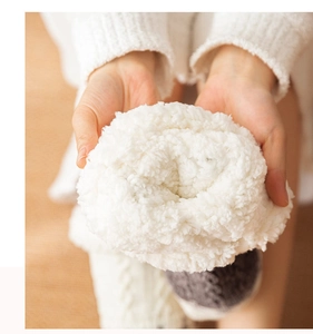 Close-up of soft white plush floor socks being held to show warm fuzzy texture