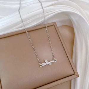 Detailed view of silver bow pendant necklace on premium brown jewelry box with satin