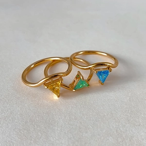 Macro view of gold plated wave rings with triangular zircon in yellow green and blue