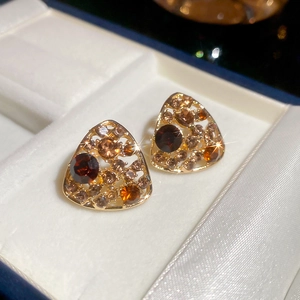 Detailed macro view of vintage gold triangular earrings with inlaid amber crystals