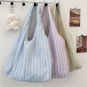 Three colorful striped canvas tote bags hanging on a white wall with metal hooks