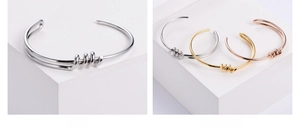 Detailed view of polished stainless steel knot bangles in silver, gold, and rose gold