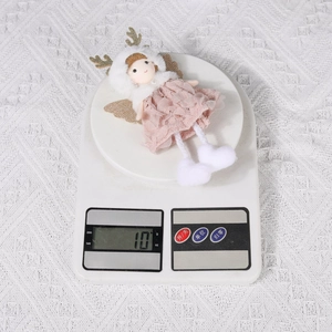 Pink lace dress angel ornament weighing 10g on a digital scale for Christmas