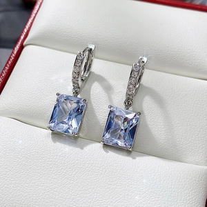 Macro view of rectangular cubic zirconia earrings in silver setting on white jewelry box