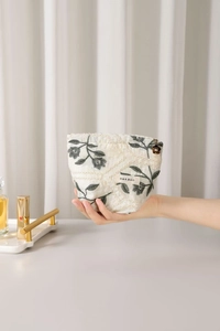 Close-up of floral embroidery on cotton linen toiletry bag with flower zipper puller