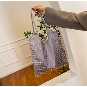 Detail of grey tote bag featuring sparkling silver rhinestone grid and leather handles