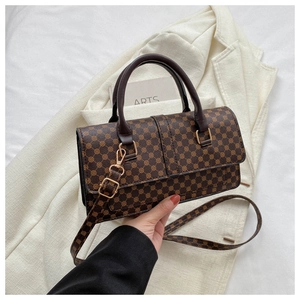 Detail of vintage brown patterned handbag with metal hardware on white suit background