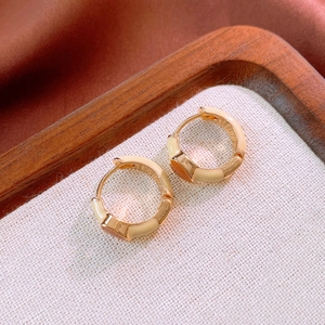 Detail of vintage gold hoop earrings with cream enamel finish on textured fabric