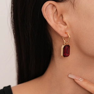 Close-up of vintage red rectangular pendant earring on model with golden hexagon clip