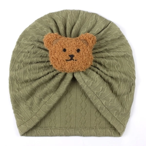 Close-up of olive green knitted baby turban hat with a cute brown teddy bear detail