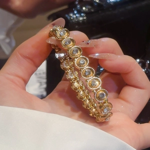 Detail of a sparkling elastic bracelet featuring golden oval links and shimmering crystals