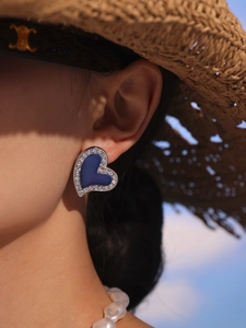Detail of luxury heart stud earring with blue enamel and sparkling cubic zirconia on model