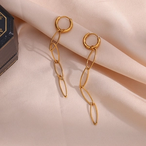 Close-up of long gold chain drop earrings on champagne silk fabric with jewelry box