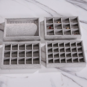 Set of 4 grey velvet jewelry organizer trays for earrings and necklaces on marble background