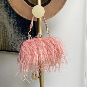 Close-up of pink ostrich feather clutch featuring a crystal ring handle and gold hardware