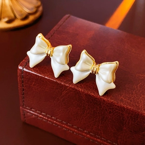 Détail de boucles d'oreilles nœud plaquées or 14K sur une boîte en cuir vintage