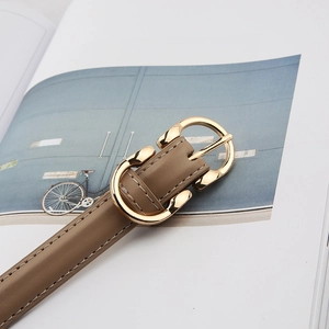 Detail of khakhi leather belt with gold metal buckle and white stitching on a magazine