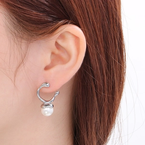 Close-up of elegant silver irregular metal earrings with pearls on a model ear