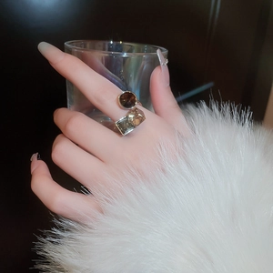 Detail of gold-plated ring with round dark and square yellow zircon stones on hand