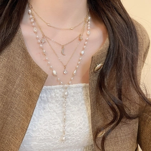 Close-up of layered gold necklace with pearl moon star pendants on elegant model