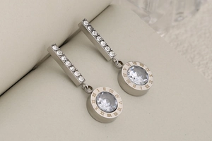 Detail of silver stainless steel drop earring with Roman numerals and pavé crystal tassel
