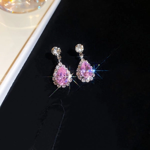 Macro shot of pink teardrop crystal earrings with silver halos on black velvet