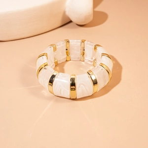 Detail of white marble resin and gold metal segmented elastic bracelet on warm background