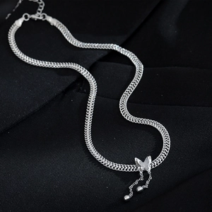 Detail of silver butterfly pendant with dangling tassels on a wide Cuban link chain