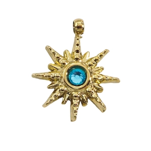 Macro shot of gold sunburst star pendant with a sparkling blue cubic zirconia center