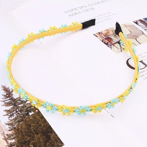 Detail of yellow daisy headband with embroidered blue and yellow flowers on lace trim
