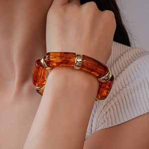 Detailed close-up of amber acrylic barrel beads with gold metallic spacers on a wrist