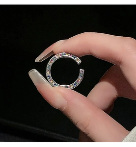 Macro shot of a C-shaped silver ear cuff with colorful zircons held by fingers