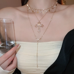Layered gold necklace with cross and star charms shown on model for elegant style