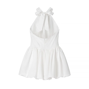 Detailed back view of white halter dress featuring a satin bow tie and pleated hem