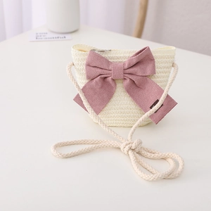 Detailed macro view of a mini straw shoulder bag with a large pink bow and rope strap