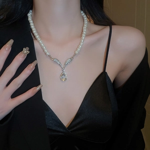Detailed view of elegant drop pearl necklace with sparkling rhinestones on model neck