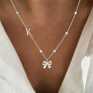 Silver stainless steel butterfly necklace with letter K and zircons on white linen shirt