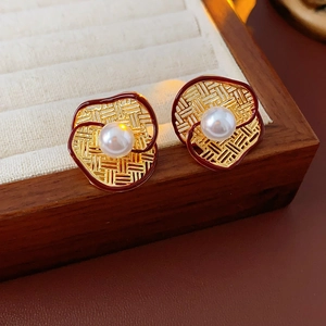 Macro shot of gold mesh flower earrings with pearls on a beige velvet jewelry tray