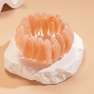Detail of peach acrylic elastic bracelet sections on a textured white stone surface