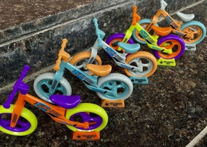 Row of four colorful toy balancing cars with display stands on a stone surface