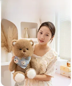 Detail of soft dark brown teddy bear plush with blue printed bandana in home setting